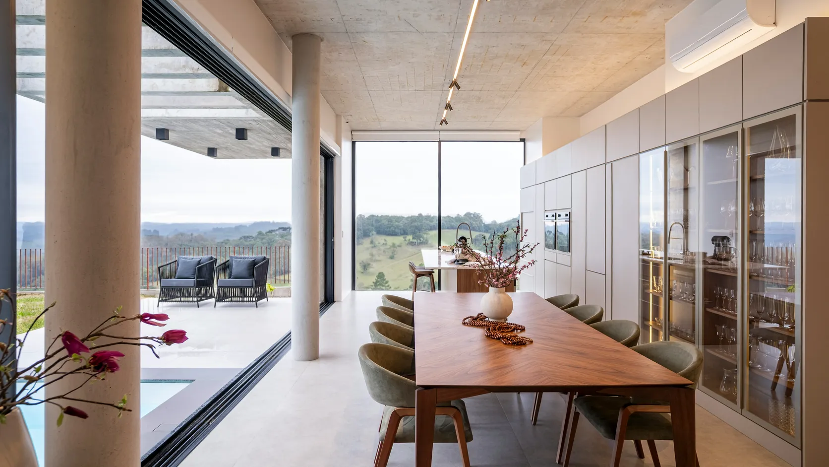 Glass wall fully open to a covered terrace and hillside view in a luxury home